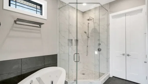 Frameless shower glass installed over a custom stone threshold