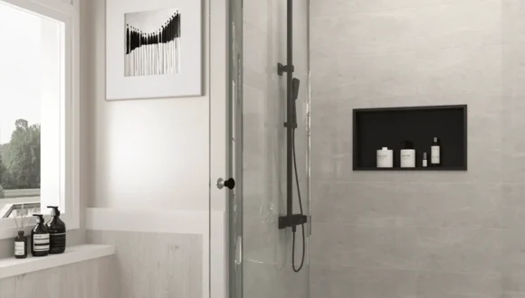 A quartz shower niche creates built-in storage without introducing a projecting caddy or a collection of small tiled edges into the shower. It may be fabricated as a complete quartz-lined opening, a solid bottom ledge, an internal shelf, or a combination of quartz pieces coordinated with the surrounding wall tile. The finished appearance can be simple, but the detail requires early planning. Shelf height, usable depth, exposed edges, vein direction, joint locations and the underlying shower assembly all affect the result. Decisions made after the wall has already been framed and waterproofed may limit the available layout or require additional joints. This guide explains how quartz shower niches are designed and fabricated, what should be confirmed before production, and how the stone fabricator’s work connects with the framing, waterproofing and tile stages of a bathroom project. Explore Custom Stone Shower Boxes Browse Quartz Surfaces Quick answer: Quartz can provide a smooth, coordinated surface for shower niche ledges, shelves and wall linings. The best result depends on selecting a quartz product suitable for the intended interior wet-area application, supporting each piece correctly and coordinating the fabrication with the shower’s separate waterproofing system. Quartz is the visible finish; it is not a substitute for the membrane and properly prepared substrate behind it. Table of Contents What Is a Quartz Shower Niche? Is Quartz Suitable for a Shower Niche? Choosing the Right Quartz Niche Shelf Layout Quartz Edge Profiles for Shower Niches Vein Direction, Joints and Pattern Layout How a Custom Quartz Shower Niche Is Fabricated Quartz Shower Niche Planning Checklist Quartz Shower Niche FAQs What Is a Quartz Shower Niche? A quartz shower niche is a recessed storage opening that uses fabricated quartz for one or more of its visible surfaces. Although the terms quartz niche, stone shower box and recessed shower shelf are sometimes used interchangeably, they can describe several different construction details. Some niches are lined entirely with quartz. Others retain tile on the back and side walls but use a solid quartz piece for the bottom ledge or shelf. The appropriate option depends on the wall construction, desired appearance, available slab material and the number of exposed edges that must be finished. Full Quartz-Lined Shower Niches In a fully lined niche, fabricated quartz pieces cover the back, sides, top and bottom of the recessed opening. This creates a consistent surface with fewer visible grout lines than a niche finished entirely with small tile pieces. A full quartz lining can work well when the niche is intended to coordinate with a quartz vanity, shower jamb or another bathroom surface. It also allows the fabricator to control exposed edges and colour transitions more carefully. However, a full lining is not automatically joint-free. Most custom niches require separate pieces to fit within the opening and allow practical installation. Joint placement, inside corners and installation tolerances should therefore be resolved before fabrication rather than concealed in a last-minute site decision. Quartz Shelves and Sills in Tiled Niches A tiled niche can use quartz selectively at the locations that benefit most from a solid piece. Common examples include: A quartz bottom sill: provides one continuous ledge beneath the bottles and toiletries. An internal quartz shelf: divides a taller niche into two usable storage levels. Quartz side and top returns: create finished edges while retaining a tile or feature panel at the back. A quartz frame: visually outlines the opening and coordinates it with other fabricated bathroom details. This mixed-material approach can reduce the amount of quartz required while keeping the most visible horizontal surfaces smooth and coordinated. It also allows a feature tile at the back of the niche to remain part of the overall shower design. Quartz may be used throughout the niche or selectively for the bottom ledge, internal shelf and exposed returns. Custom-Fabricated vs. Prefabricated Quartz Niches A prefabricated niche has a predetermined outside and inside size. It can simplify the wall preparation stage, but its shelf positions, proportions, colour and edge details may offer limited customization. A custom-fabricated quartz niche is made around project-specific dimensions. It can be coordinated with the height of shampoo bottles, the tile module, the location of wall studs and the pattern of other quartz surfaces in the bathroom. Custom fabrication also makes it possible to use slab remnants when the available piece has the correct colour, thickness and usable dimensions. The critical distinction is that the fabricated quartz and the recessed waterproof enclosure are not necessarily the same component. A waterproofed niche or prepared wall cavity may be completed first, after which quartz pieces are measured, fabricated and installed as the visible finish. The project team should confirm the sequence before final measurements are taken. Is Quartz Suitable for a Shower Niche? Quartz can be a practical option for a shower niche, particularly when a smooth appearance, consistent pattern and limited surface absorption are priorities. Engineered quartz is commonly used for interior bathroom surfaces, and certain manufacturers also identify their products for applications such as shower surrounds, wall cladding, recessed shelving or bathroom shelves. That does not mean every quartz colour, finish, thickness or brand should automatically be specified for every shower detail. Product documentation, fabrication requirements and warranty conditions should be reviewed for the exact material being considered. Where Quartz Performs Well A suitable quartz product can offer several advantages inside a properly constructed shower niche: Consistent colour and pattern: useful when coordinating the niche with a vanity countertop or other fabricated components. Smooth, easy-to-wipe surfaces: particularly helpful on shelves that collect soap residue and water droplets. Fabricated edge options: exposed ledges and returns can be cut and finished before arriving at the installation site. Low routine maintenance: engineered quartz generally does not require the periodic sealing associated with many natural stones. Custom sizing: shelves and lining pieces can be produced for the measured opening rather than forcing the design around a stock accessory. These advantages relate to the quartz finish itself. Corners, perimeter joints, supports and transitions still require appropriate installation materials and workmanship. What Quartz Does Not Replace Quartz should not be described as the waterproofing system for the shower wall. Water management takes place behind the visible finish through the properly prepared substrate, membrane, niche enclosure and sealed transitions to the surrounding shower assembly. This distinction matters because a smooth quartz surface may still have joints around its perimeter and where separate pieces meet. If water reaches those joints, the assembly behind the quartz must already be designed to manage moisture safely. The stone fabricator should coordinate with the contractor responsible for framing, wall preparation, waterproofing and tile installation. Responsibilities should be clear before fabrication so that quartz pieces are not used to conceal an incomplete or incompatible substrate. Confirming Product and Finish Suitability Before approving a quartz slab for a shower niche, confirm: Whether the specific manufacturer permits the proposed interior wet-area application Whether the selected finish is appropriate for frequent exposure to water and bathroom cleaning products Which adhesives and sealants are compatible with both the quartz and waterproofing system Whether the selected thickness can be supported at shelves and projecting edges How cut edges, corners and the underside of shelves will be finished Whether the warranty requires fabrication or installation by an approved professional Planning note: Choose the exact quartz product before finalizing the niche dimensions. Slab thickness, pattern scale, available remnant size and edge treatment can all affect the usable interior space and final appearance.
